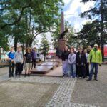 Grupa uczniów i prowadzący stoją przed pomnikiem ks. Brzóski w Sokołowie Podlaskim podczas warsztatów tworzenia Questu.