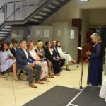 Bożena Mrozowska-Gozdołek odczytująca biografię Jana Kochanowskiego w tle publiczność siedząca na krzesłach.