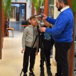 Prowadzący warsztaty oraz dwóch chłopców przy statywie i gimbalu w dziale dla dorosłych.