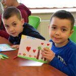 Dzieci prezentują własnoręcznie wykonane prace plastyczne w bibliotece.