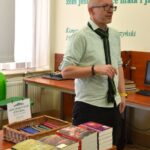 Piotr Brysacz – założyciel Wydawnictwa Paśny Buriat stoi przy stoliku z książkami.