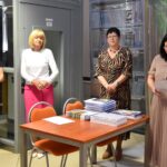 Cztery kobiety stoją przy stole na którym leżą książki i dyplomy dla uczestników konkursu recytatorskiego im. Kornela Makuszyńskiego. Kobieta z prawej strony przy w ręku protokół z wynikami konkursu.