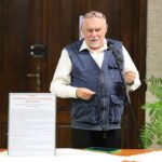 Pan Ryszard Szczepan Przytulski opowiada o zalewajce podczas Festiwalu Literatury Kulinarnej w sokołowskiej Bibliotece. Stoi przy mikrofonie, obok plansza z cytatem z filmu „Jak rozpętałem II wojnę światową” i opisem potrawy.