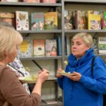 Uczestniczki Festiwalu Literatury Kulinarnej w sokołowskiej Bibliotece degustują regionalne potrawy. W tle regał z książkami kucharskimi i literaturą kulinarną, m.in. „Z miłości do tradycji. Smaki Ziemi Siedleckiej”, „Zdrowie na talerzu” i „100 przepisów na potrawy Wielkanocne”.