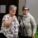 Panie Teresa Nazarczuk i Barbara Tekieli podczas Festiwalu Literatury Kulinarnej w sokołowskiej Bibliotece. Obie stoją przy mikrofonie, uśmiechnięte, gotowe do rozmowy z publicznością. Na stole przed nimi leży notatnik i ozdobna serwetka.