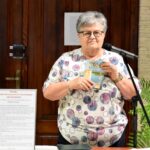 Teresa Nazarczuk opowiada o tradycjach kulinarnych Podlasia. Kobieta trzyma w ręku książkę pod tytułem Nadburzańskie smaki.