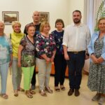 Osiem osób stoi razem w pomieszczeniu biblioteki, pozując do grupowego zdjęcia. Są to uczestnicy jeden z grup kursów komputerowych.