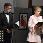 Dwie młode osoby, kobieta i mężczyzna czytają wiersze do mikrofonu.