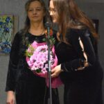 Maria Szymańczuk oraz jej córka, która przemawia przez mikrofon. Obie kobiety swoją na scenie.