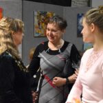 Dwie kobiety, autorka Maria Szymańczuk odbiera gratulacje. Na pierwszym planie scenie przygląda się młoda trzecie kobiet.