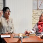 Dwie kobiety siedzą przy stole i prowadzą rozmowę.