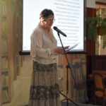 Wiesława Kwiek odczytuje wiersz. Ubrana jest w strój mający przypominać strój romski.