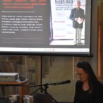 Na pierwszym planie Ilona Flażyńska prelegentka na spotkaniu, przedstawia książkę autorstwa Stanisława Stankiewicza.