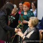 Małgorzata Iwańska-Kania wręcza byłym pracownikom biblioteki czerwone róże.