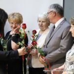 Małgorzata Iwańska-Kania wręcza byłym pracownikom biblioteki czerwone róże.