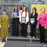 Trzy osoby z najstarszej grupy wiekowej trzymają w rękach nagrody w konkursie. Obok nich stoi jury oraz pani dyrektor biblioteki Małgorzata Iwańska-Kania.